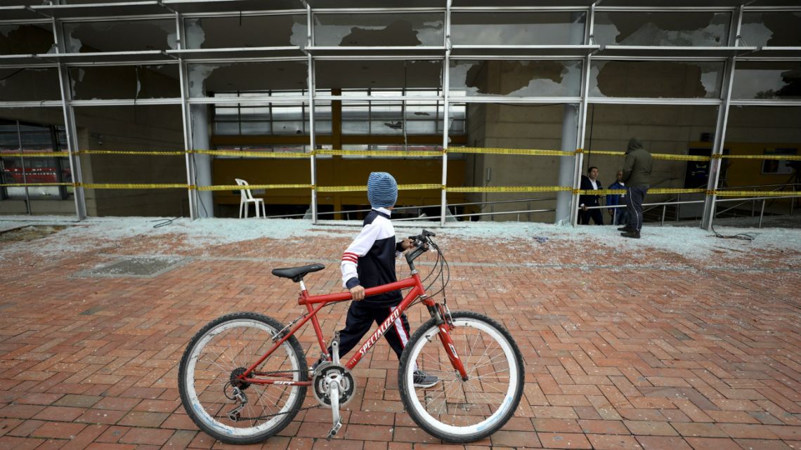 A boy walks past a bus station damaged by anti-government demonstrators, in Bogota, Colombia, Friday, Nov. 22, 2019. Protesters attacked the station Thursday during a nationwide strike called by labor unions, students and teachers to protest everything from economic inequality to violence against social leaders