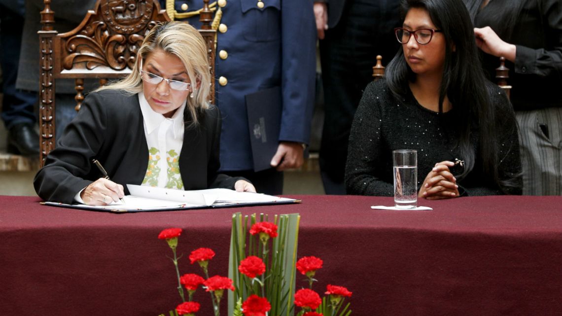 Bolivia's interim President Jeanine Anez, left, signs into law a bill to hold new elections beside the President of the Senate Monica Eva Copa in La Paz, Bolivia.