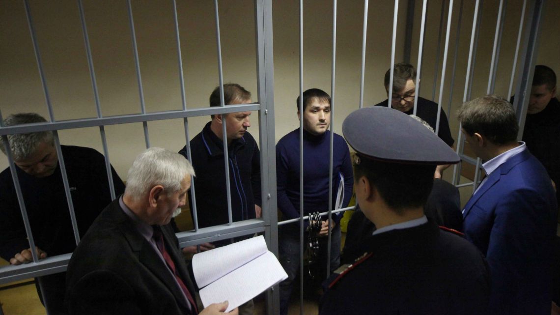 Suspects stand inside a cage during preliminary hearings in a courtroom in Moscow, Russia, Friday, November 29, 2019. A Moscow court has opened preliminary hearings in the case of suspects accused of attempting to smuggle nearly half a ton of cocaine in diplomatic luggage from Argentina to Russia. 