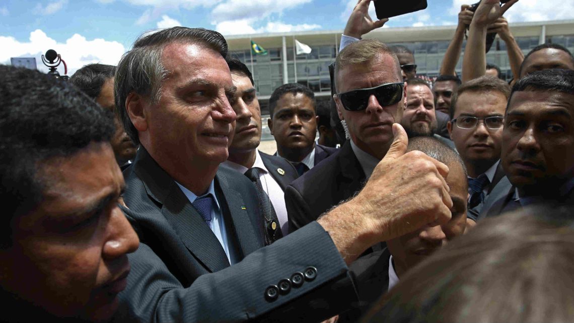 Brazil's President Jair Bolsonaro flashes a thumbs up as he greets supporters after attending a Changing of the Guard at the Planalto Presidential Palace, in Brasilia, Brazil, Thursday, November 28, 2019. 