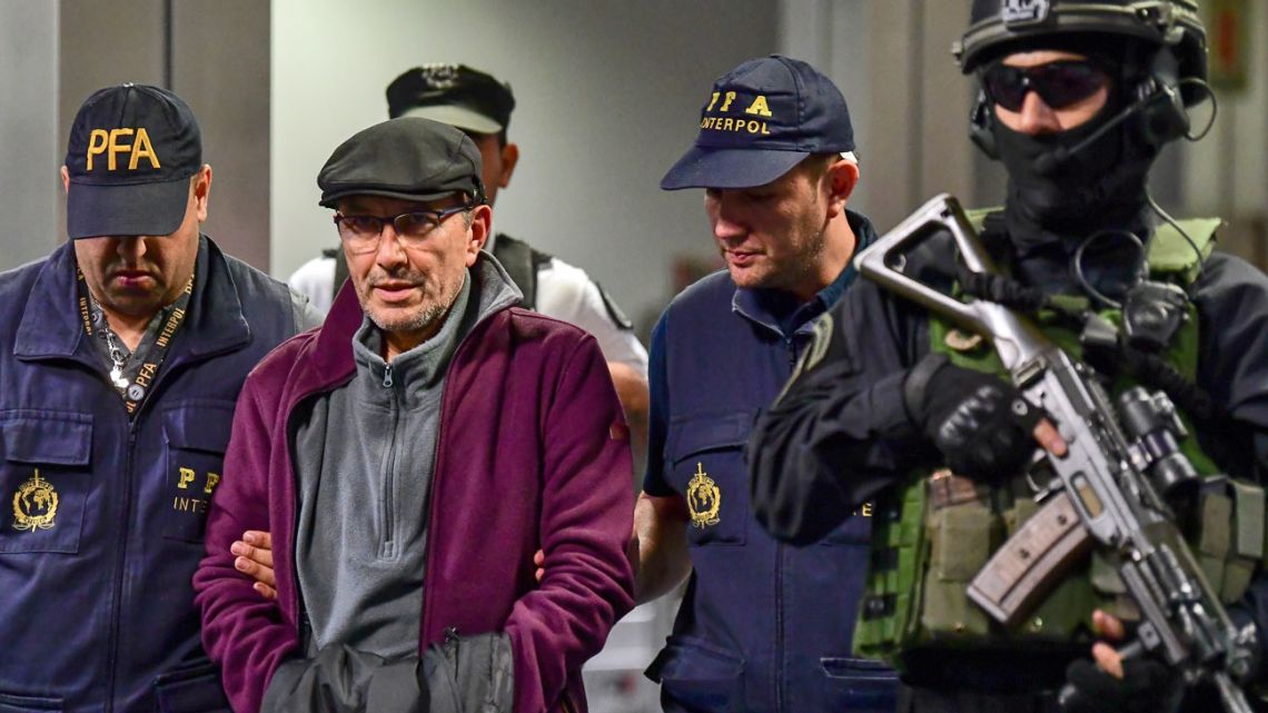 Mario Sandoval (2-L) is escorted by police officers upon his arrival at Ezeiza airport in Buenos Aires on December 16, 2019, after France extradited him to face trial over the disappearance of a student. Sandoval took part in more than 500 cases of kidnappings, torture and murder during the 1976-83 military dictatorship.