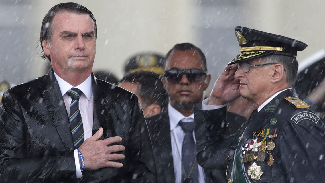 Brazil's President Jair Bolsonaro puts his hand over his heart as Army Commander Edson Leal Pujol salutes during the playing of the national anthem during a ceremony to mark Army Day in Brasilia, Brazil.