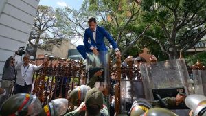 Juan Guaidó, Venezuela's opposition leader, tries to climb the fence to enter the compound of the National Assembly, after he and other opposition lawmakers were blocked by police from entering a session to elect new Assembly leadership in Caracas, Venezuela, Sunday, January 5, 2020. 