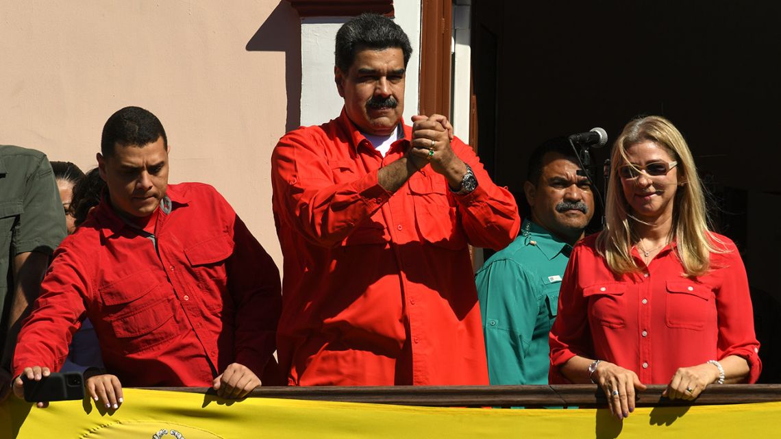 Venezuelan President Nicolás Maduro (centre), flanked by his wife Cilia Flores (right), gestures to supporters from a balcony at the Miraflores Palace.