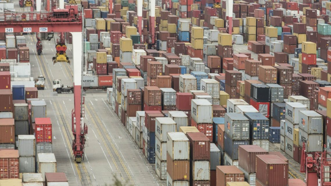 Container trucks move past shipping containers at the Yangshan Deep Water Port in Shanghai, China, on Tuesday, February 4, 2020.