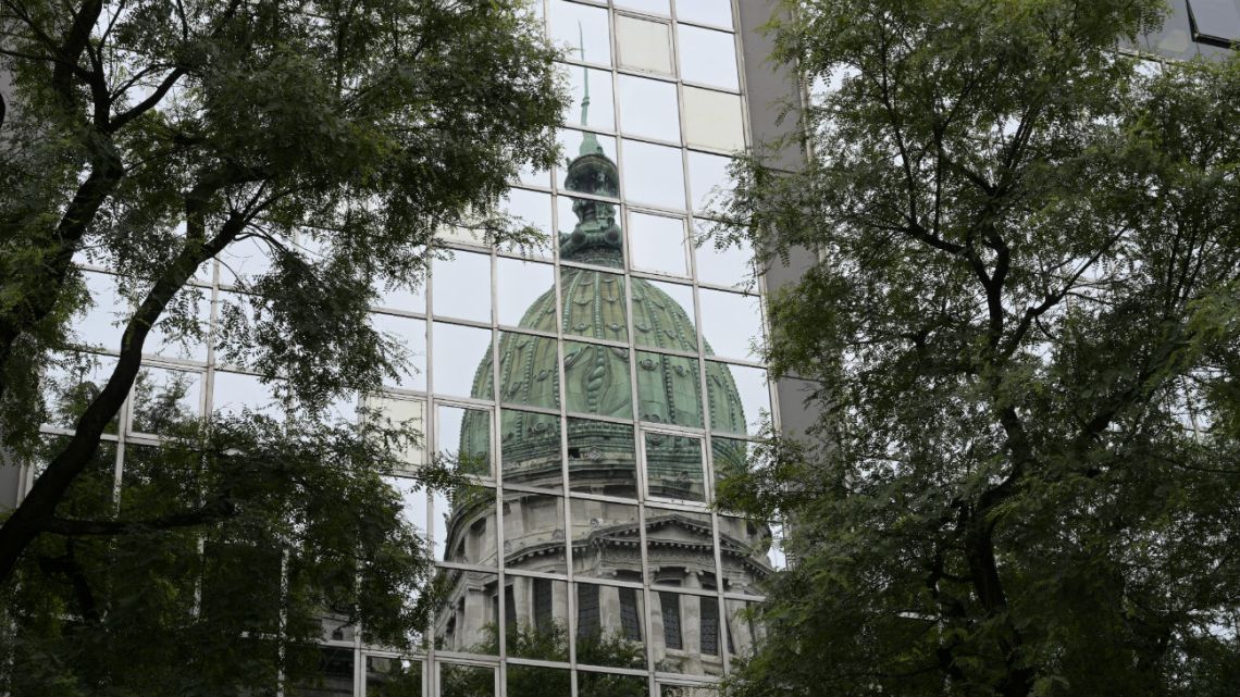 The dome of the Argentine Congress is seen reflected on the windows of the Congress annex while senators debate a bill to renegotiate the public external debt, in Buenos Aires, on February 5, 2020.