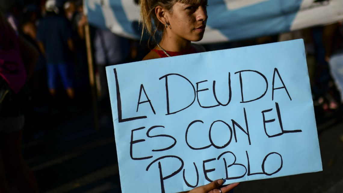 People protest against the International Monetary Fund (IMF) outside of the Argentine Congress, on February 12, 2020. The sign partly reads, "the debt is with the people." 