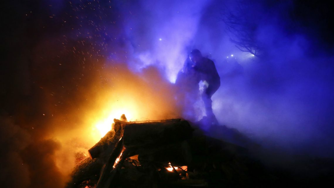 A protester, who planned to stop buses carrying passengers evacuated from the Chinese city of Wuhan, kindles a fire outside Novi Sarzhany, Ukraine, Thursday, February 20, 2020.