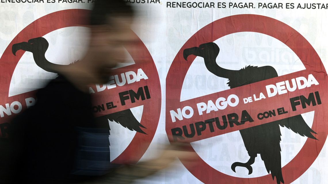 A man walks by posters against the International Monetary Fund (IMF) in Buenos Aires on February 19, 2020. 