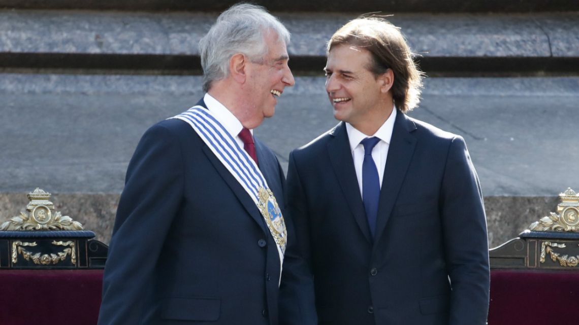 Uruguay's new President Luis Lacalle Pou, right, smiles at outgoing president Tabaré Vazquez before receiving the presidential sash