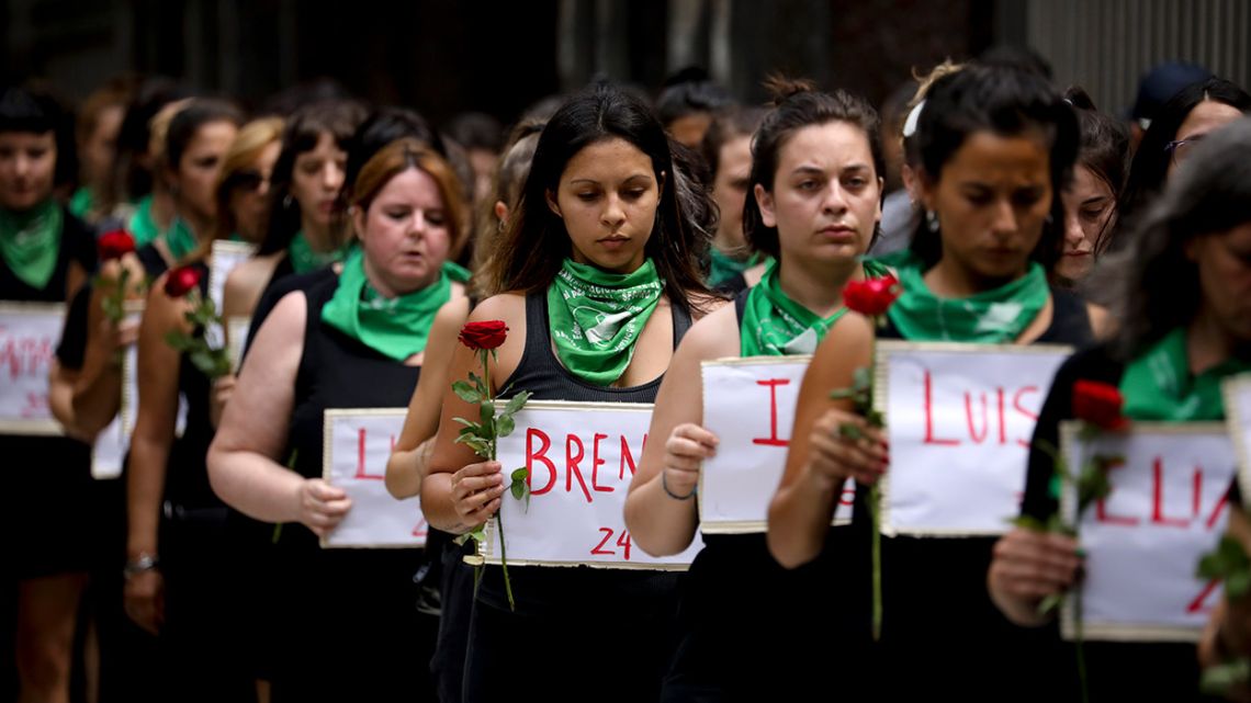 Women march from the National Congress to the Plaza de Mayo on International Women's Day, each one carrying a flower and a sign with names of those women killed in 2020.