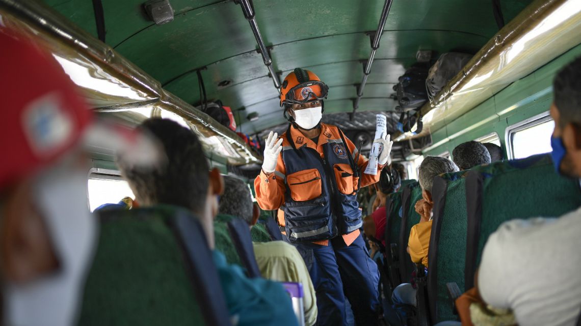 A member of the Venezuelan civil protection agency explains commuters symptoms and preventive measures for the new coronavirus in Caracas, Venezuela, Sunday, March 15, 2020.