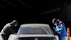 Argentine officials wearing face masks check a car entering from Chile at the Horcones border crossing in Mendoza, Argentina, after the two countries restricted control at their borders as a precaution against the spread of the new coronavirus.