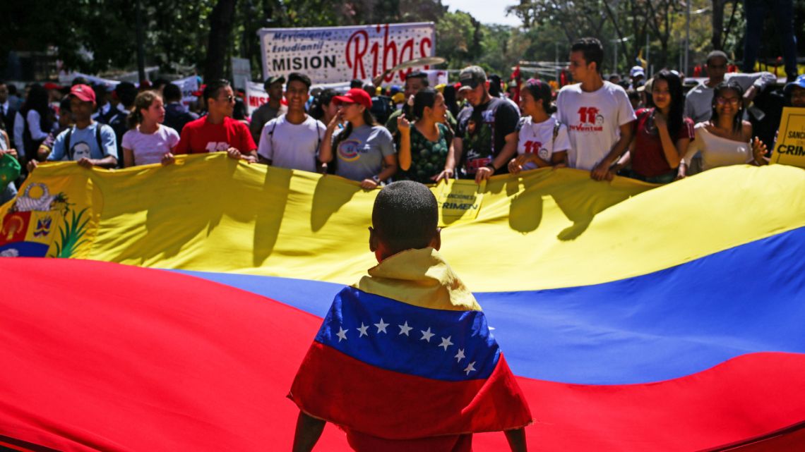 Supporters of the Venezuelan President Nicolas Maduro hold a Venezuelan flag while taking part in a demonstration heading to the National Assembly, in Caracas, on March 10, 2020. 