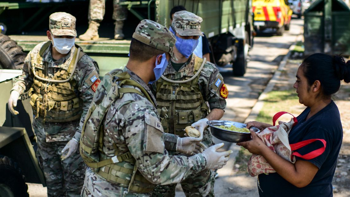 Soldiers give out food to people in a deprived neighbourhood of the municipality of Quilmes, on the outskirts of Buenos Aires, on March 24, 2020, amid the novel coronavirus, COVID-19, pandemic.