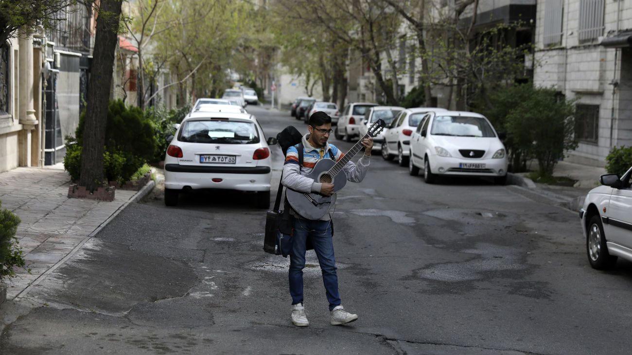 Un música callejero toca la guitarra en una calle vacía de la capital. 