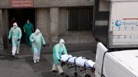 Un trabajador de la salud lleva un cuerpo en una camilla frente al hospital Gregorio Marañón en Madrid.
