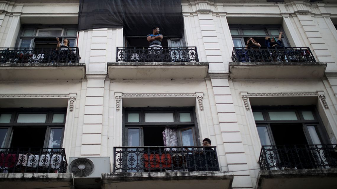 People stand at their balconies in Buenos Aires, Sunday, March 29, 2020. 