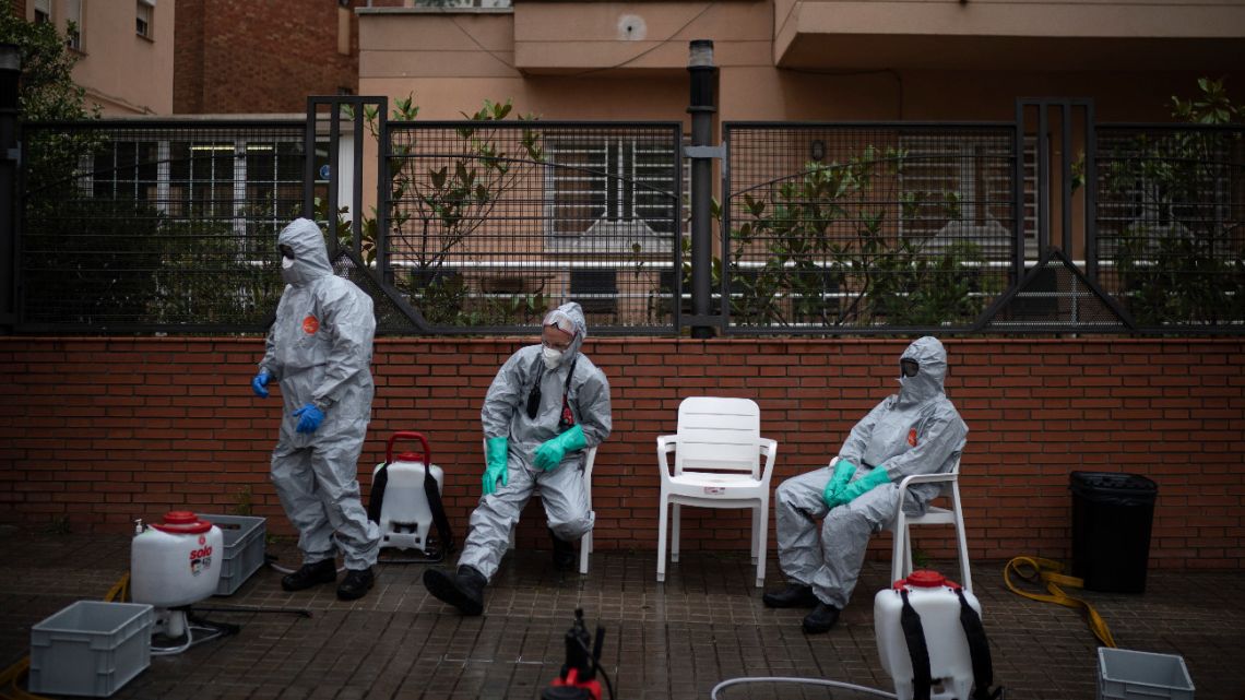 Firefighters wearing protective suits wait outside a nursing home before disinfecting it in efforts to prevent the spread of the new coronavirus in Barcelona, Spain, Monday, March 30, 2020. 