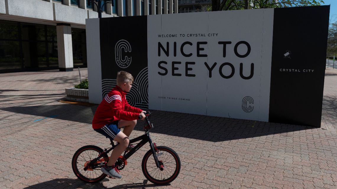 A boy bikes past a sign next to a closed office building in Crystal City, where a majority of business have closed because of the coronavirus pandemic, in Arlington, Virginia on April 3, 2020.