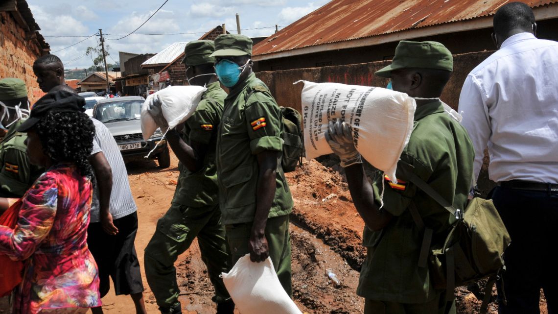 Members of the country's armed forces, the Uganda People's Defence Force (UPDF), help to distribute foodstuffs to people affected by the lockdown measures aimed at curbing the spread of the new coronavirus, in the Bwaise suburb of the capital Kampala, Uganda Saturday, April 4, 2020.