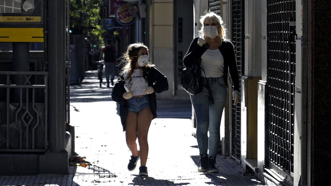 A woman and a girl wear face masks while walking in Buenos Aires.