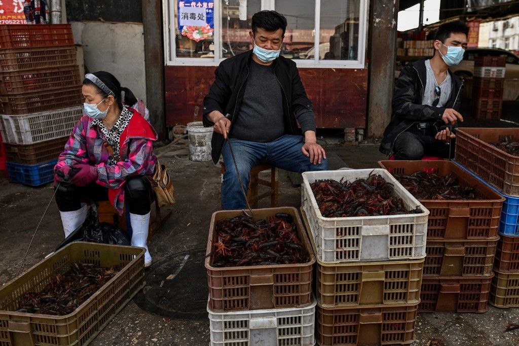 En un gran mercado de alimentos en la ciudad china de Wuhan los carteles prohíben la venta de animales salvajes y aves de corral, mientras los altavoces reproducen una y otra vez mensajes que celebran la "victoria" sobre el nuevo coronavirus.