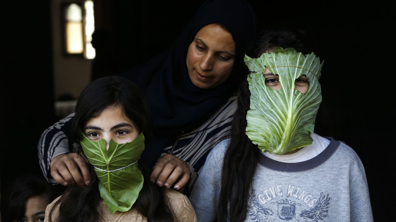 Una madre palestina entretiene a sus hijos con máscaras improvisadas hechas de repollo