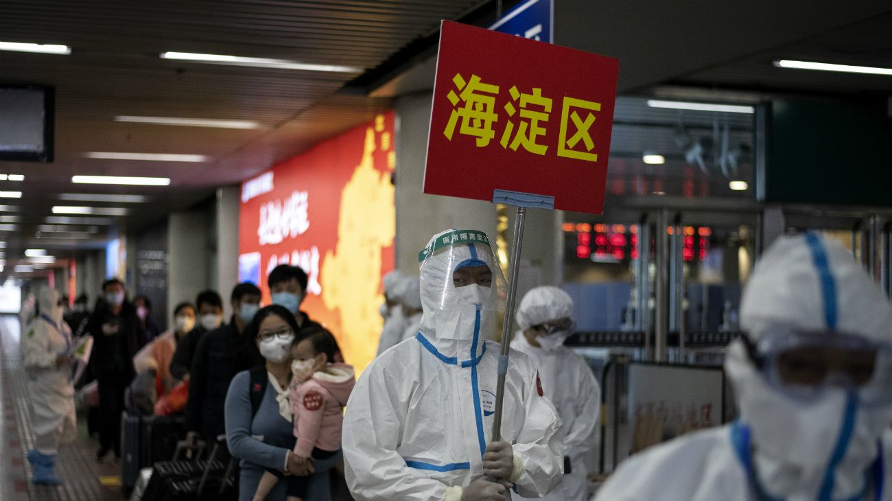 China: El personal guía a los viajeros que llegan de Wuhan a los buses rumbo a sus lugares de cuarentena en Beijing 