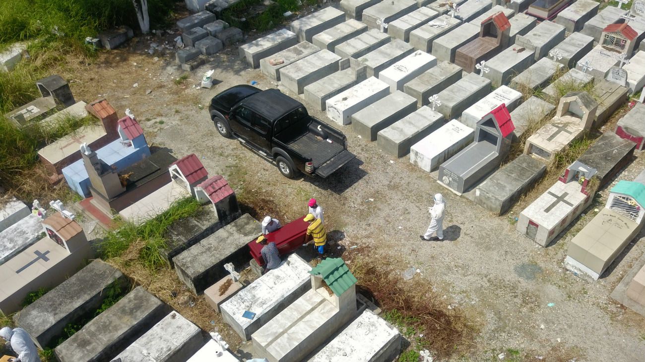 Guayaquil, Ecuador: Trabajadores enterrando un ataúd en el cementerio de Maria Canals