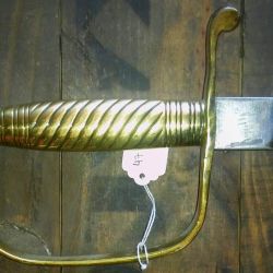La empuñadura es de bronce, formando una sola pieza entre el pomo y la guarda. 