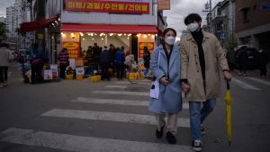 La gente usa barbijos y tapabocas en la calle y recorriendo un mercado de Seúl