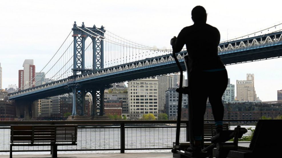 Solitaria, una personas ejercita este jueves 23 de abril en Nueva York, con el puente de Manhattan de fondo.