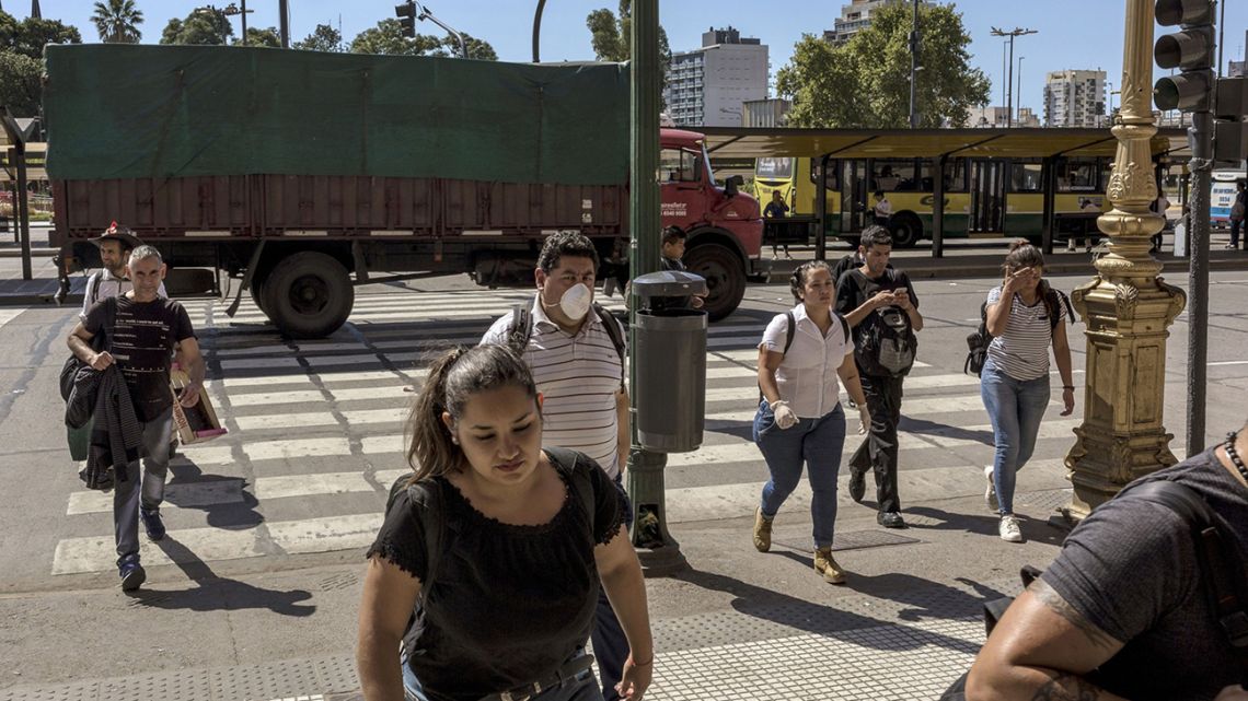 Porteños, some wearing face masks, cross a street in Buenos Aires.