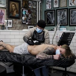 Con una máscara protectora, el artista Ruben en el estudio de tatuajes  | Foto:afp