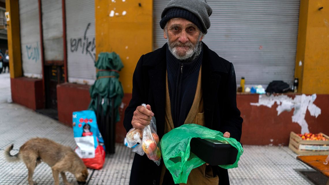 A man poses for a photo holding food he received from a group of neighbours who have formed to help people in need facing hardship amid the new coronavirus pandemic, in the financial district of Montevideo, Uruguay, Saturday, April 25, 2020. 