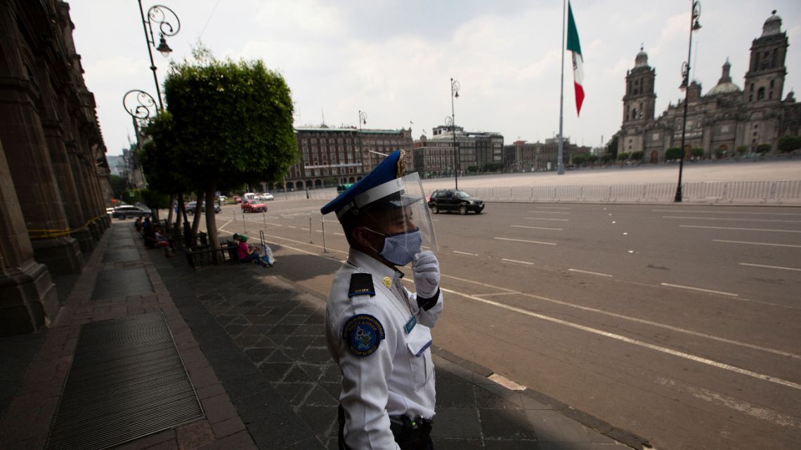 A police officer, wearing a protective face mask, a face shield and disposable gloves as a precaution against the spread of the new coronavirus, stands guard at City Hall in Mexico City, Saturday, April 25, 2020. 