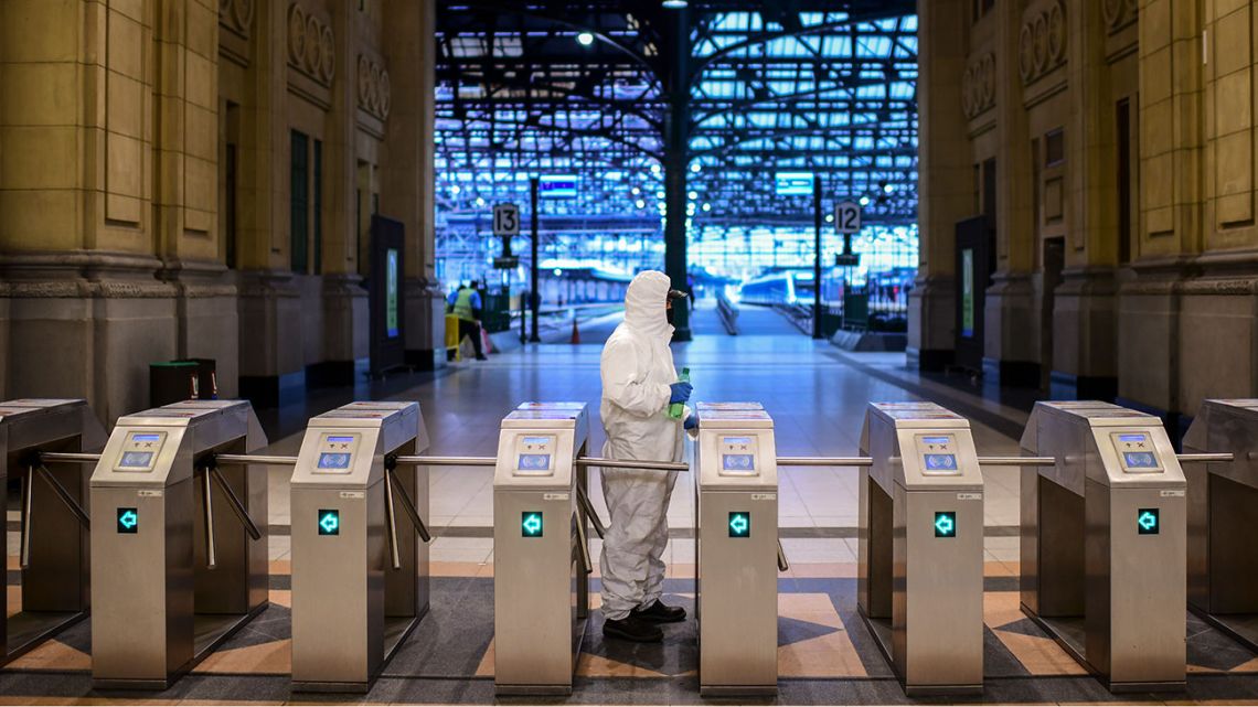A employee of Trenes Argentinos disinfects the ticket gate at Constitución train station, in Buenos Aires, on April 24, 2020 amid the Covid-19 coronavirus pandemic. 
