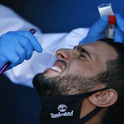  275/5000 Un profesional médico del Ministerio de Salud de Palestina toma un hisopo de la nariz de un hombre dentro de una ambulancia durante una prueba aleatoria para detectar la enfermedad del coronavirus COVID-19 en personas que ingresan a la ciudad de Hebrón en la Cisjordania ocupada el 30 de abril de 2020. (Foto por HAZEM BADER / AFP) | Foto:AFP