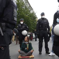 Un manifestante sentado en la calle está rodeado de policías con máscaras faciales y pidiéndole que se vaya el 1 de mayo de 2020 a la plaza Rosa-Luxemburg-Platz en Berlín, el lugar donde una llamada  | Foto:AFP