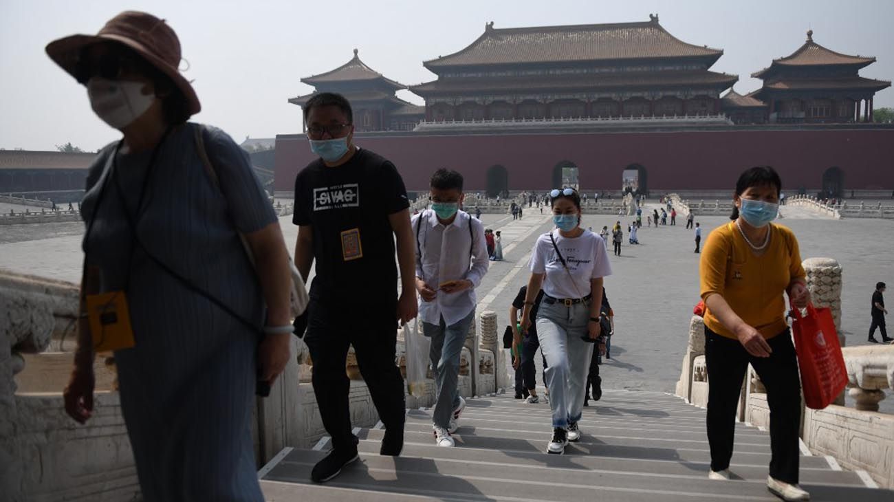 Los visitantes usan mascarillas como medida preventiva contra el Coronavirus, mientras caminan por la Ciudad Prohibida, el antiguo palacio de los emperadores de China.