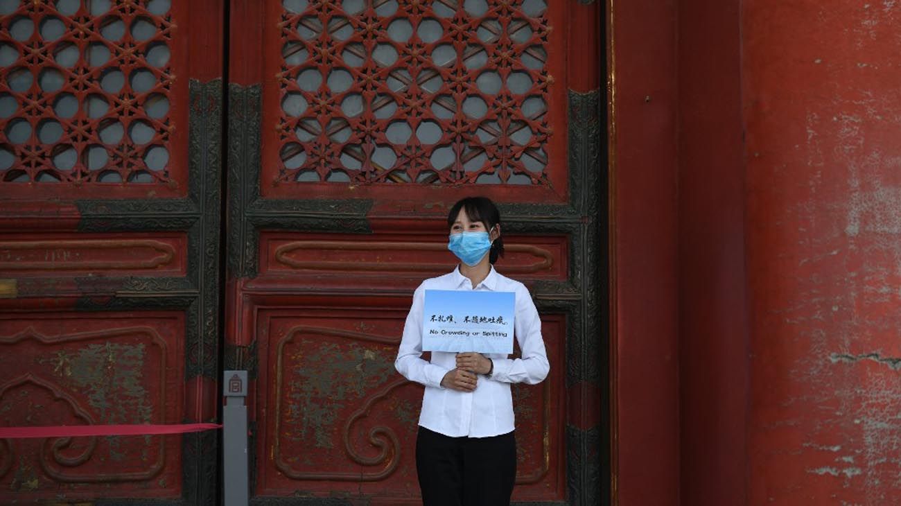 Los visitantes usan mascarillas como medida preventiva contra el Coronavirus, mientras caminan por la Ciudad Prohibida, el antiguo palacio de los emperadores de China.