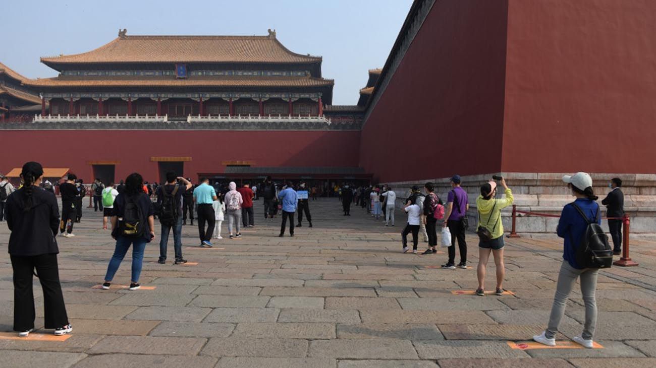 Los visitantes usan mascarillas como medida preventiva contra el Coronavirus, mientras caminan por la Ciudad Prohibida, el antiguo palacio de los emperadores de China.