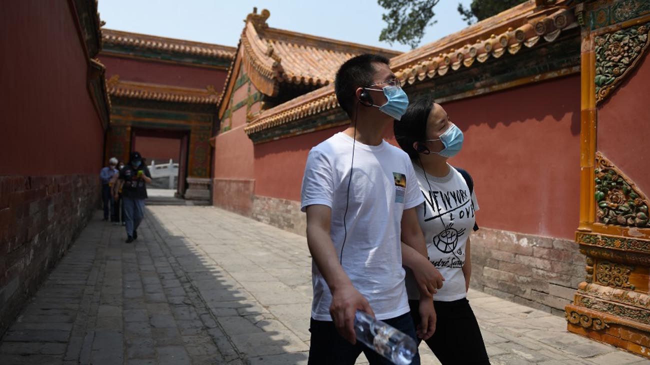 Los visitantes usan mascarillas como medida preventiva contra el Coronavirus, mientras caminan por la Ciudad Prohibida, el antiguo palacio de los emperadores de China.