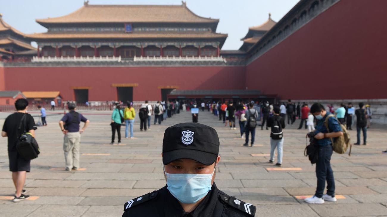 Los visitantes usan mascarillas como medida preventiva contra el Coronavirus, mientras caminan por la Ciudad Prohibida, el antiguo palacio de los emperadores de China.