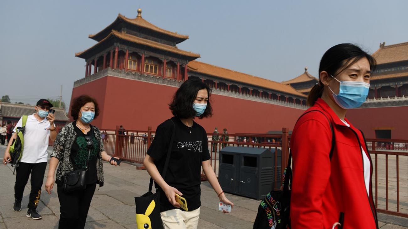 Los visitantes usan mascarillas como medida preventiva contra el Coronavirus, mientras caminan por la Ciudad Prohibida, el antiguo palacio de los emperadores de China.