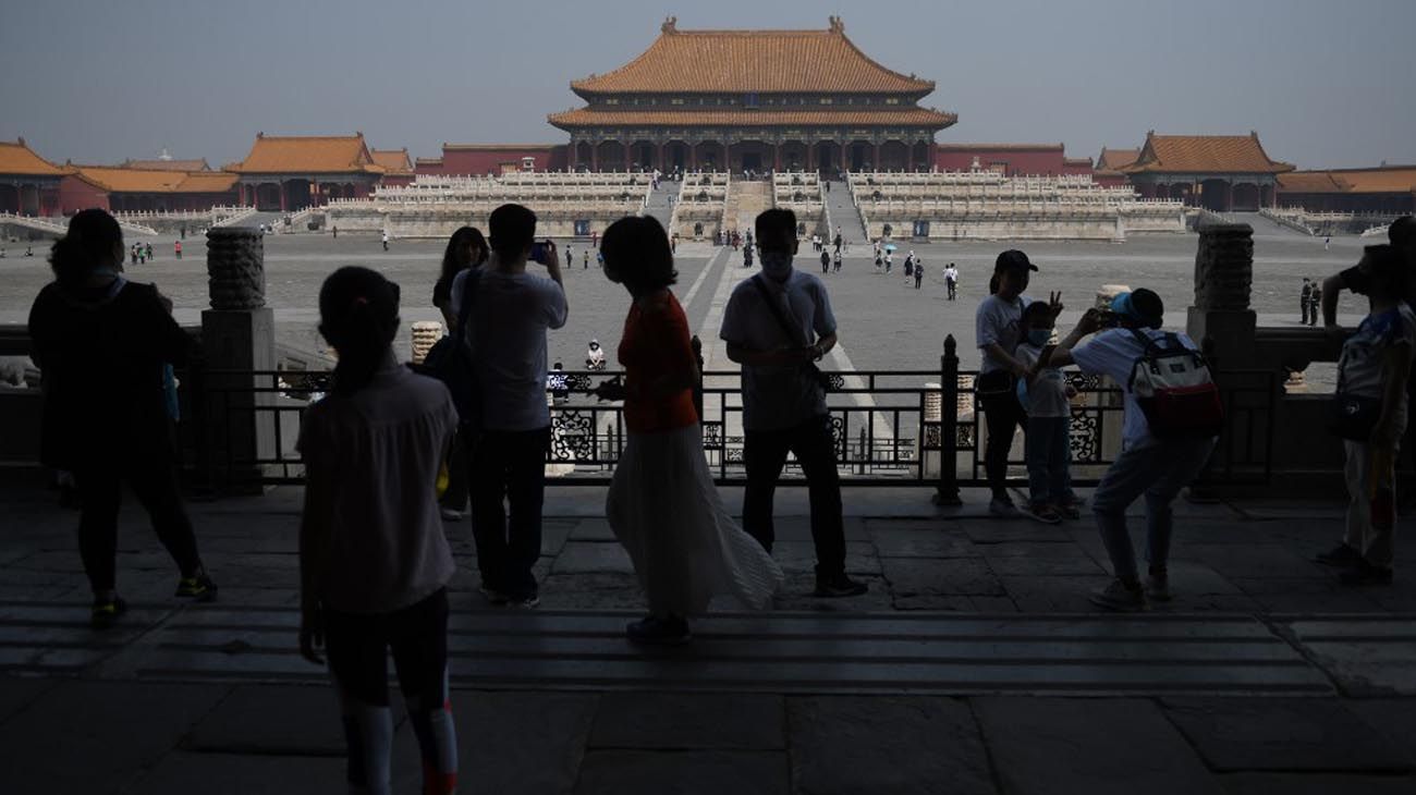 Los visitantes usan mascarillas como medida preventiva contra el Coronavirus, mientras caminan por la Ciudad Prohibida, el antiguo palacio de los emperadores de China.