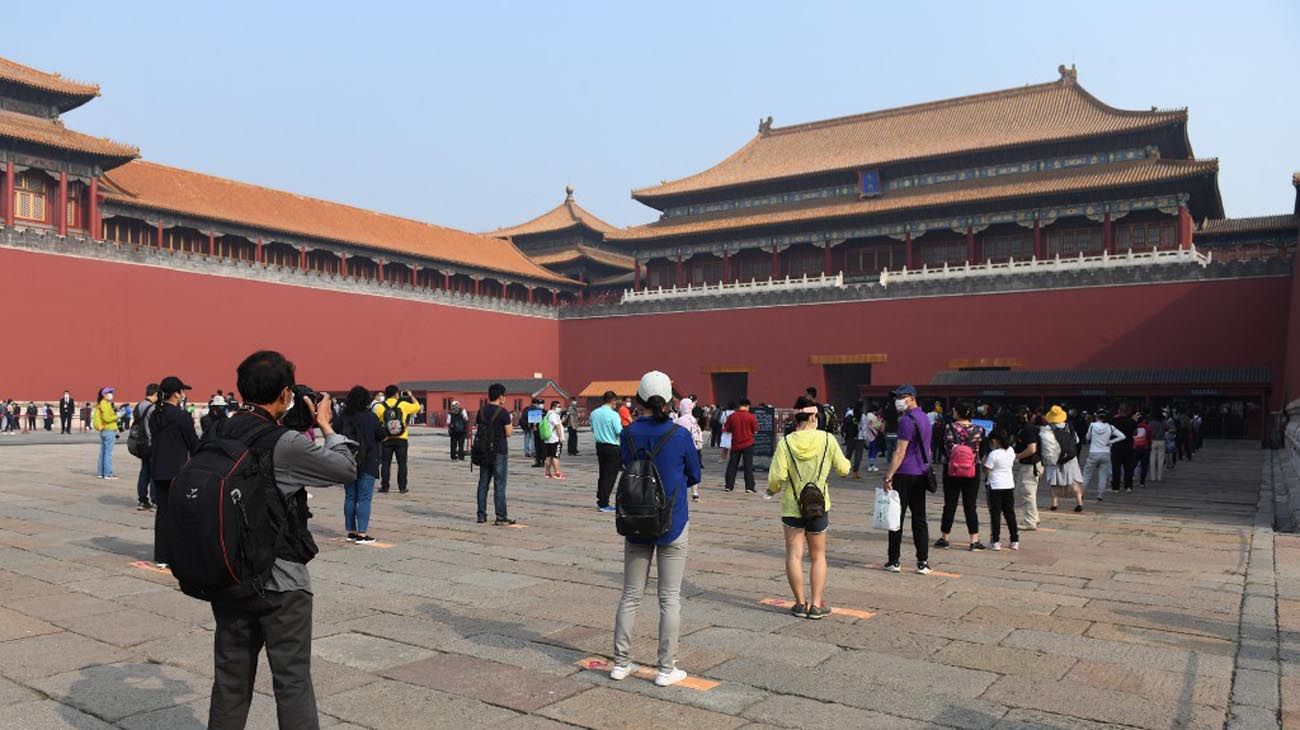 Los visitantes usan mascarillas como medida preventiva contra el Coronavirus, mientras caminan por la Ciudad Prohibida, el antiguo palacio de los emperadores de China.