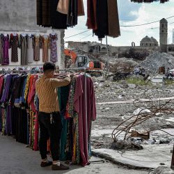Un vendedor ambulante arregla la ropa que se exhibe en el área del mercado Sarj Khaneh en la antigua ciudad de Mosul, en el norte de Irak, mientras que la dañada Iglesia Católica Romana de Nuestra Señora de la Hora se ve en el fondo, el 3 de mayo de 2020, a medida que el país se relaja. restricciones establecidas para la pandemia de coronavirus COVID-19. / AFP / Zaid AL-OBEIDI | Foto:AFP