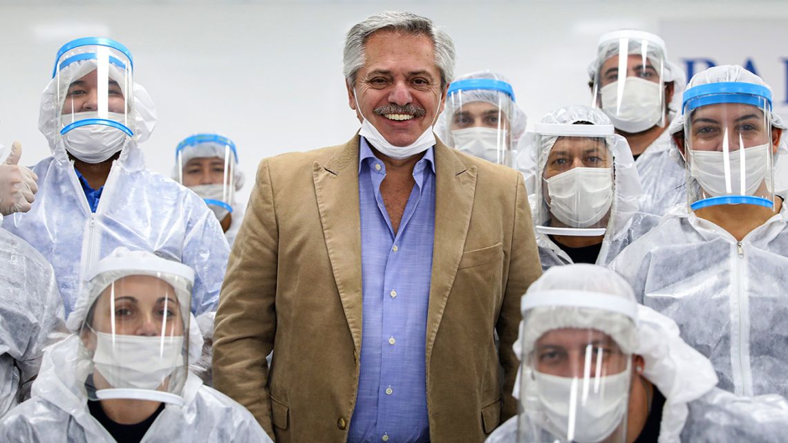 Handout photo released by the Presidency shows President Alberto Fernández (centre) posing with workers of an automotive industry now making chinstraps and caps to fight against the spread of the novel coronavirus, on the outskirts of Buenos Aires, on May 1, 2020.